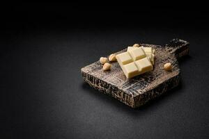 Delicious sweet white chocolate broken into cubes on a wooden cutting board photo