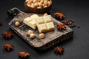 Delicious sweet white chocolate broken into cubes on a wooden cutting board photo