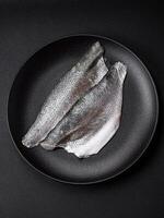 Raw sea bass fish fillet with salt, spices and herbs on a ceramic plate photo