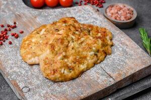 Delicious fried chicken breast in batter with mustard, salt, spices and cheese photo