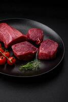 Juicy raw beef with spices, salt and herbs on a dark concrete background photo