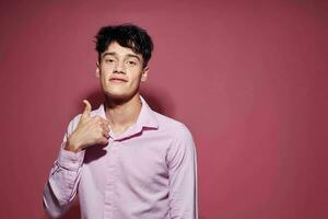 pretty man in a pink shirt gesturing with his hands pink background unaltered photo