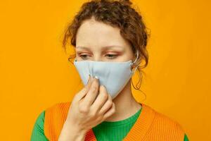 alegre mujer en un amarillo camiseta médico máscara proteccion rosado antecedentes inalterado foto