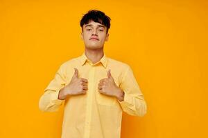 Cheerful young man in a yellow shirt gestures with his hands emotions photo