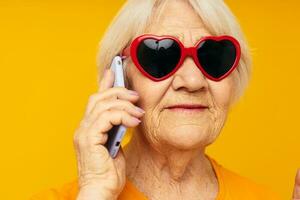 Portrait of an old friendly woman posing face grimace with a phone in hand cropped view photo