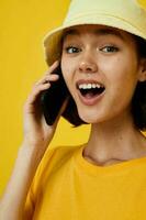 atractivo mujer en un amarillo sombrero juventud estilo casual hablando en el teléfono aislado antecedentes foto