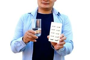 Man holds glass of water and blister of medicine , isolated on white background. Concept , Health care, health problem, sickness and remedy. Basic self take care, treatment at home when get sick. photo