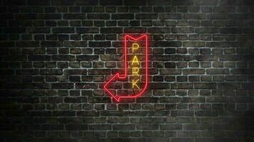 Park neon real signboard on bricks wall background. Down and left direction arrow signboard in red neon color with yellow park letters in the middle video