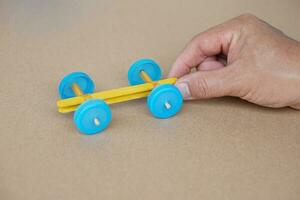 Hand hold handmade toy racing car made from ice cream sticks and bottle caps. Concept, Recycling kids toy. Easy to do, creative DIY craft that kids can do. Fun lesson photo