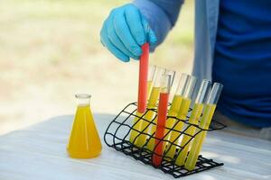 Close up hand wear blue glove holds test tube of colorful substances to do science experiment outdoor. Concept, Chemistry subject, science project work. Research. Experiment, education. photo