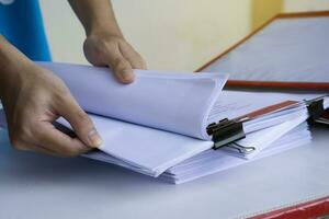 Close up man  hands open paper document.Concept, office work. Document management. Checking correct of works.  Campaign using both side of paper for environment. Reuse reuse and recycle. photo