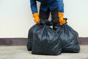 Closeup man holds black plastic bag that contains garbage inside. Concept , Waste management. Environment problems. Daily chores. Throw away rubbish . Sorting type of garbage. photo
