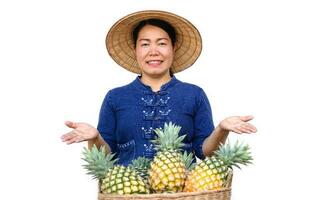 asiático mujer granjero usa sombrero, azul camisa, hacer mano gesto a presente piña frutas concepto, granjero es contento y orgulloso desde haciendo orgánico agricultura. tailandés agricultor. foto