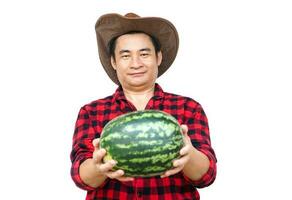 Handsome Asian man wear hat, red plaid shirt, holds watermelon fruit, isolate on white. Concept, Agriculture occupation.Thai farmer, grow and sell watermelon fruits as economic crops. photo