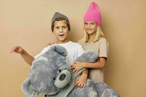 Photo of two children in multi-colored hats entertainment posing beige background