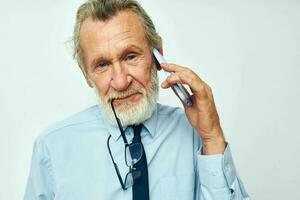 Photo of retired old man in a shirt with a tie with a phone technology light background