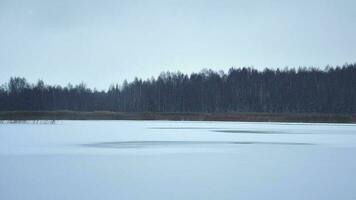 hermoso panorama del lago congelado con pasos de pescadores en el lago helado con hielo nuevo y frágil. peligros en el hielo y pesca en hielo.pov pescador video