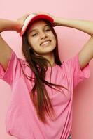 alegre joven niña con un gorra en su cabeza en un rosado camiseta foto