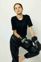 hermosa niña en boxeo guantes en negro pantalones y un camiseta estilo de vida inalterado foto