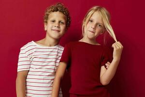 Small children good mood standing next to posing red background photo