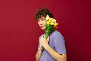 linda adolescente participación un amarillo ramo de flores de flores púrpura camisetas aislado antecedentes inalterado foto