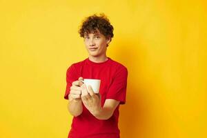 guy with red curly hair white mug in the hands of a drink yellow background unaltered photo