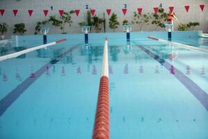 un vacío Deportes piscina con un rojo divisor camino. azul agua en el nadando piscina. foto