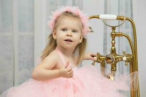 pequeño niña en un inteligente rosado vestido. un hermosa dos años de edad niño. foto