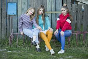 Girls in the style of the nineties. Three country girls are sitting on a wooden bench. photo