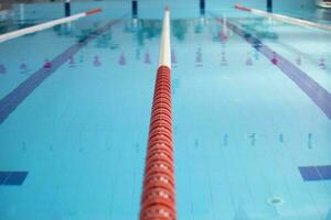 un vacío Deportes piscina con un rojo divisor camino. azul agua en el nadando piscina. foto