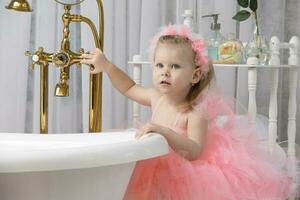 pequeño niña en inteligente rosado en el baño. foto