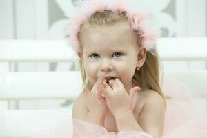 retrato de un pequeño alegre niña con rosado arcos dos años de edad niño. foto