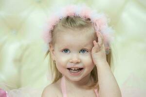 retrato de un pequeño alegre niña con rosado arcos dos años de edad niño. foto