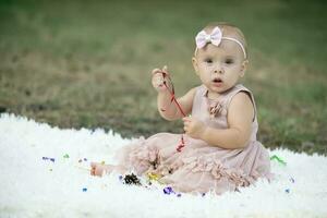 A beautiful little girl on a walk in a summer park. One year old child. Sweet baby. photo