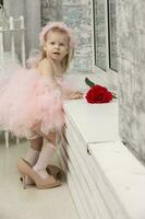 Little funny girl in a smart pink dress and high heel shoes. photo