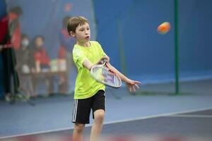 A boy with a tennis racket on the court plays tennis. photo