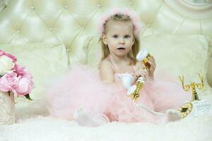 dos años de edad niño. hermosa pequeño niña en un elegante rosado vestir con un retro teléfono. foto