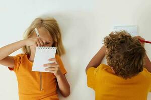 chico y niña dibujo en cuadernos acostado en el piso infancia estilo de vida inalterado foto