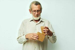 antiguo hombre con lentes demuestra un caja en un ligero estudio uno foto