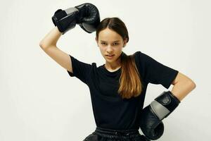joven hermosa mujer en boxeo guantes en el piso en negro camiseta aptitud formación foto