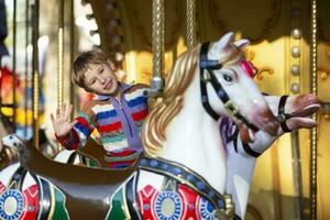 Handsome little boy is riding a carousel. A child on a horse carousel. photo