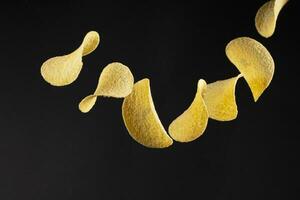 Chips on a black background. Flying potato chips. photo