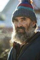 The face of an elderly man with a beard in a knitted hat. photo