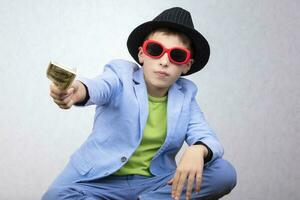 A cute, rich boy with glasses is holding dollars. Financial education, young millionaire, investments, loans, winnings photo