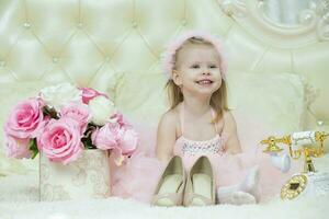 Two-year-old child. Happy little girl in elegant pink dress with retro phone and mom's shoes. Going to a party or bachelorette party. photo