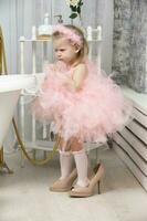 A little funny girl in smart pink and high heels is standing in the bathroom and crying. photo