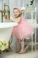 A little funny girl in smart pink and high heels stands in the bathroom and laughs .. photo