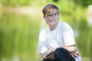 Handsome intelligent boy in glasses looks at the camera and smiles. photo