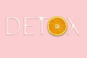 Body detoxification and healthy eating concept. Yellow natural orange in the word DETOX from letters on a pink background. photo