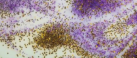 Festive or glamorous background. Gold and purple sparkles scattered on a white background. photo